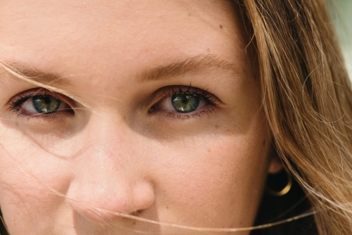 eye close up with wind blown hair across the face - Australian Stock Image