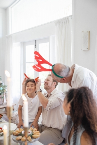 Family at Christmas table making jokes with prawns - Australian Stock Image