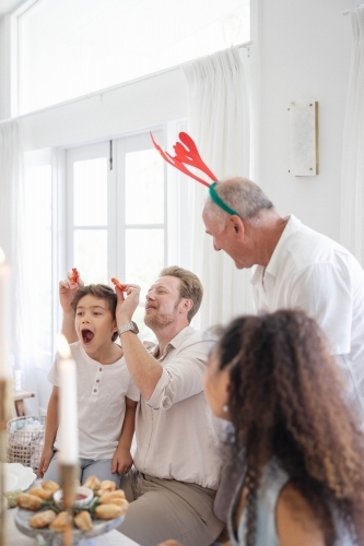 Family at Christmas table making jokes with prawns - Australian Stock Image