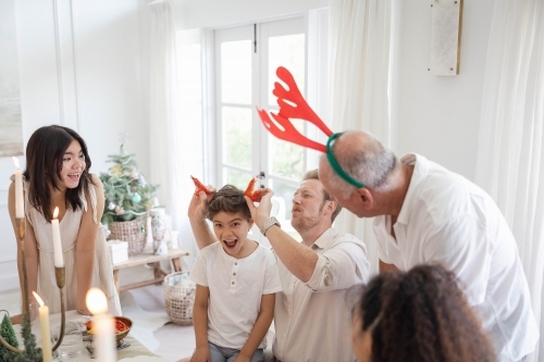 Family at Christmas table making jokes with prawns - Australian Stock Image