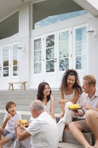 Family eating snacks on backyard stairs - Australian Stock Image