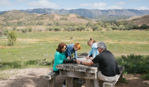 Family having a rest at a wooden table in the outback - Australian Stock Image