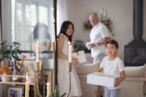 Family holding Christmas presents with candelabra in foreground - Australian Stock Image