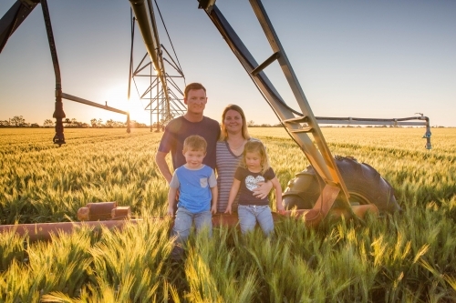 Family in wheat field paddock with pivot irrigation system - Australian Stock Image