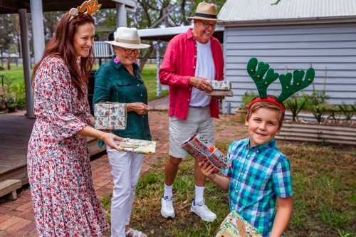 family members exchanging gifts at Christmas family gathering - Australian Stock Image