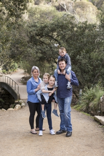 Family of five standing in bushland posing for photo - Australian Stock Image