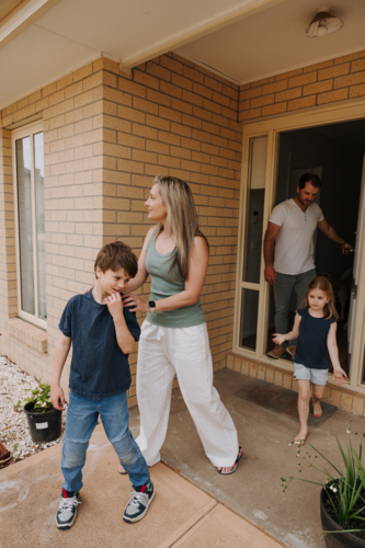 Family of four coming out of the house. - Australian Stock Image