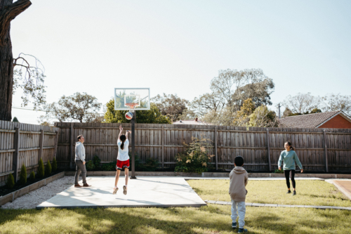 Family playing basketball in their yard. - Australian Stock Image