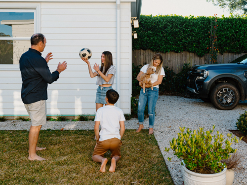 Family playing with a soccer ball in the garden. - Australian Stock Image
