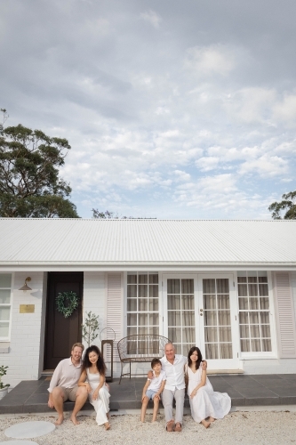 Family sitting together on front porch - Australian Stock Image