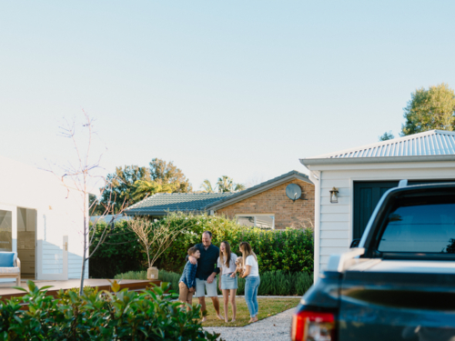 Family standing outside their house in the yard. - Australian Stock Image