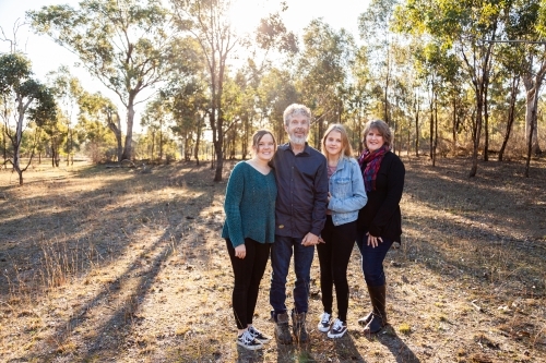 Family with teen and adult daughters standing together in paddock - Australian Stock Image