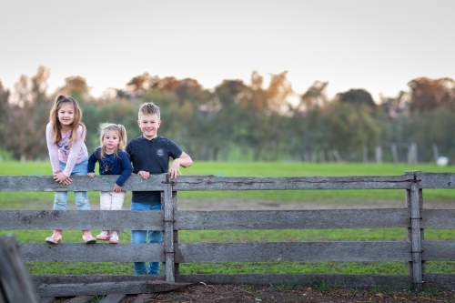 Farm kids standing on sheep yard rails - Australian Stock Image