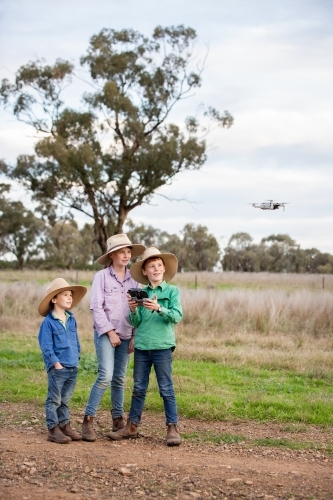 Farm kids using a drone in the paddock - Australian Stock Image