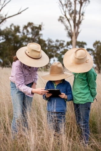 Farm kids using an ipad in the paddock - Australian Stock Image