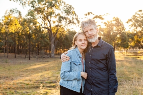 Father and daughter hug together in paddock with copy space - Australian Stock Image