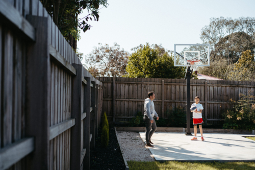 Father and daughter playing basketball in their yard - Australian Stock Image