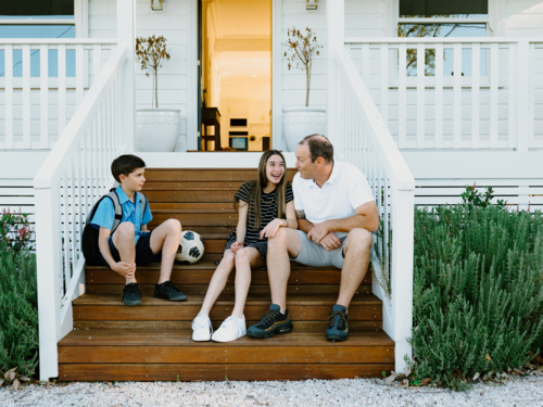 Father and his children sitting on the porch wooden steps. - Australian Stock Image