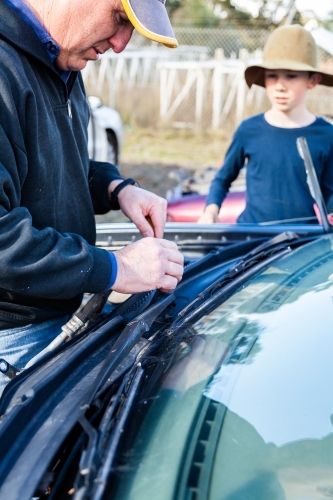 Father and son at wreckers pulling apart broken car for parts - Australian Stock Image