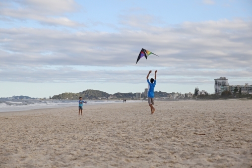 Father and son flying kite on the beach
