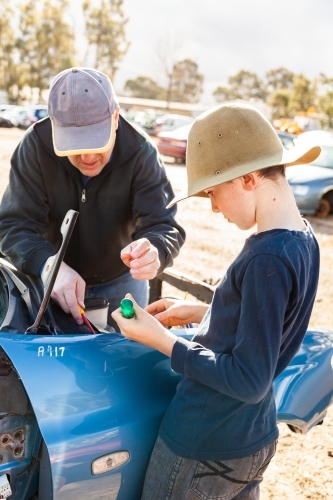 Father and son in wreckers pulling apart smashed car for parts - Australian Stock Image