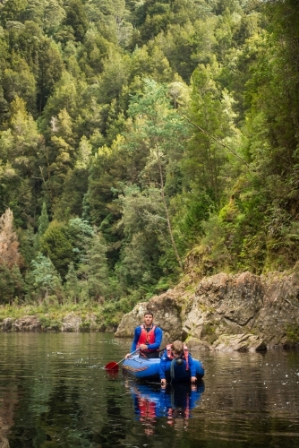 Father and son kayaking down tranquil lush river - Australian Stock Image