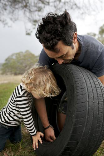 Father and son putting together a tyre swing in country backyard