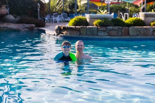 Father and son swimming in pool happy smiling on holidays - Australian Stock Image