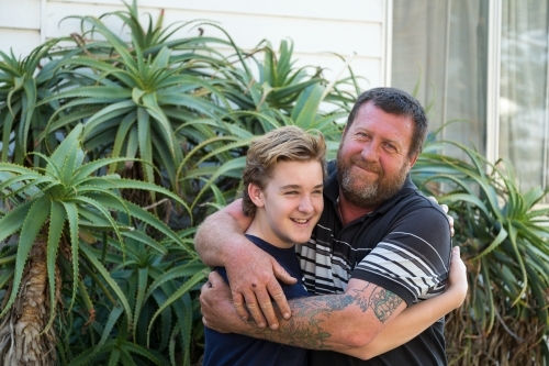 Father embracing teenaged son - Australian Stock Image