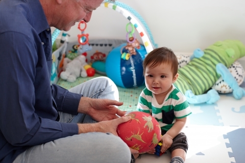 Father playing with baby boy in living room - Australian Stock Image