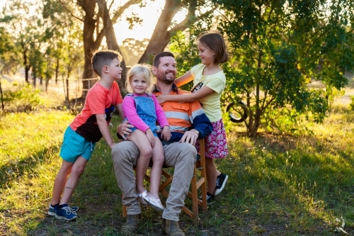 Father relaxing with three of his kids outside - Australian Stock Image