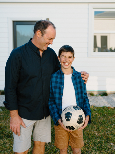 Father standing beside his son holding a soccer ball. - Australian Stock Image