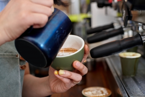 Female barista pouring coffee into a cup - Australian Stock Image