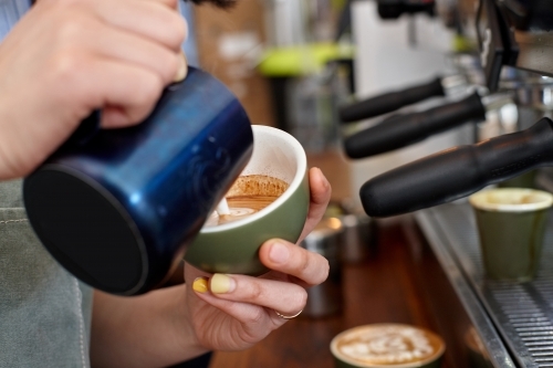 Female barista pouring coffee into cup - Australian Stock Image