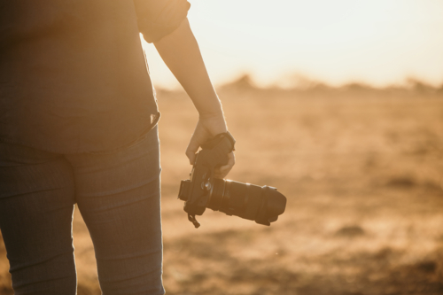 Female facing away holding camera beside body - Australian Stock Image