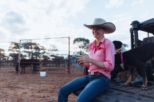 Female farmer sitting on the back of vehicle - Australian Stock Image