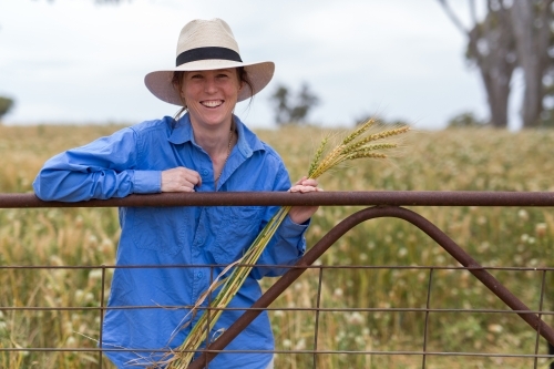 Female farmer standing at a gate on a farm - Australian Stock Image