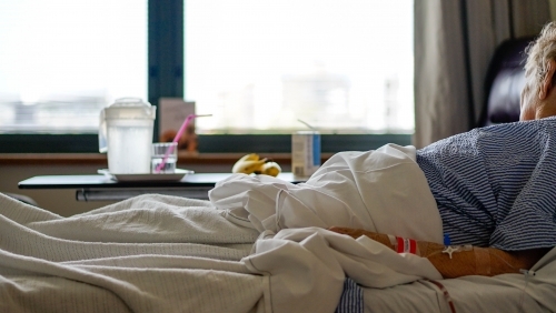 Female patient in hospital looking out window - Australian Stock Image