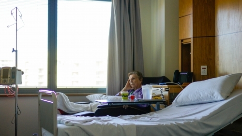 Female patient sitting in chair watching tv - Australian Stock Image