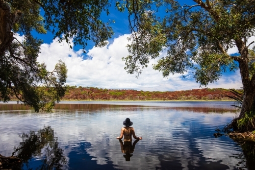 Female standing in the dark reflective water of a lake on Fraser Island - Australian Stock Image