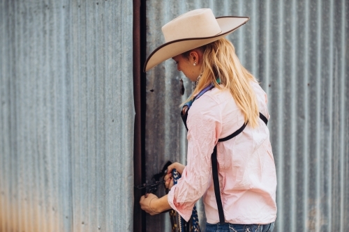 Female teenager farmworker closing shed door - Australian Stock Image