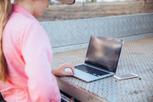 female teenager using technology in a farm paddock - Australian Stock Image