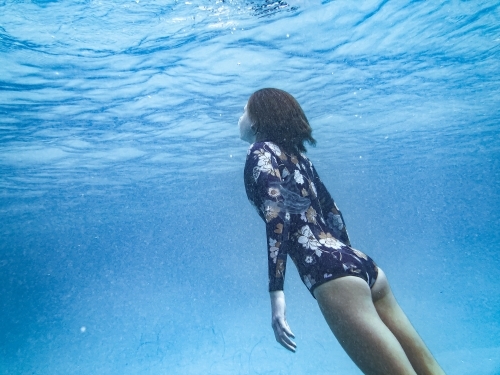 Female underwater in ocean wearing full piece swimsuit - Australian Stock Image