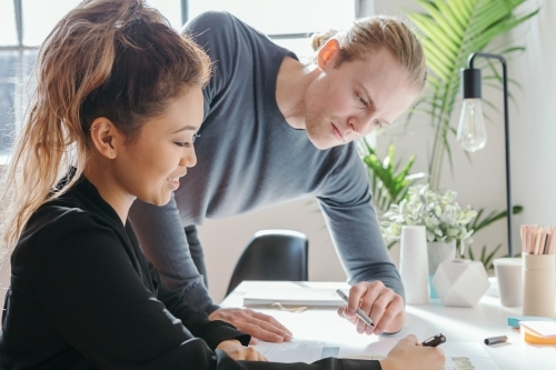 Female worker explaining something to a male team member - Australian Stock Image