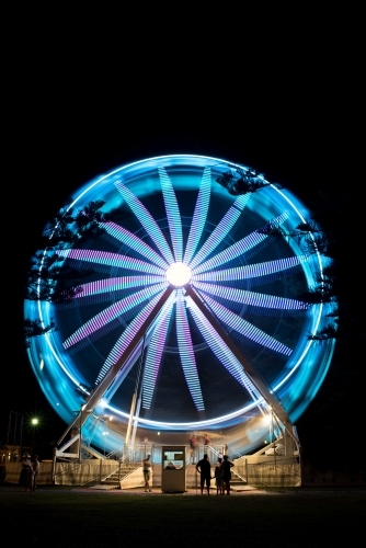 Ferris wheel at night with silhouetted people in foreground