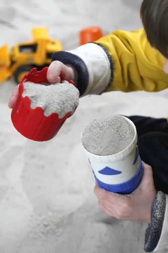 Filling cups with sand in sandpit - Australian Stock Image