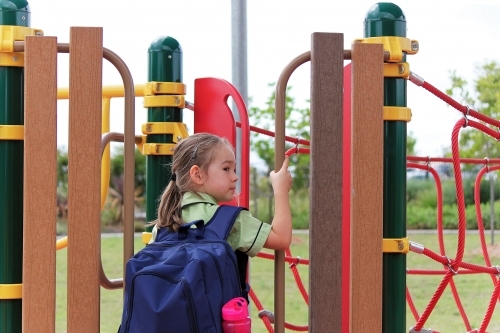 First day at school with school bag over a young girl's shoulders - Australian Stock Image