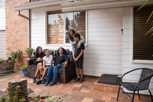 First nations family sitting together on couch outside - Australian Stock Image