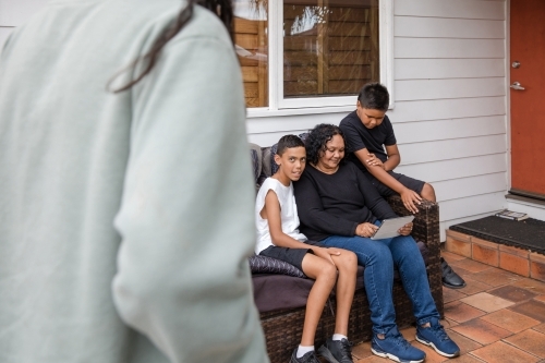 First nations family sitting together on couch outside - Australian Stock Image