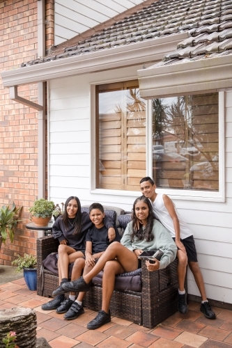 First nations family sitting together on couch outside - Australian Stock Image